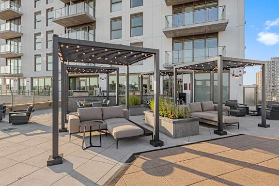A modern outdoor seating area with a pergola and planters.