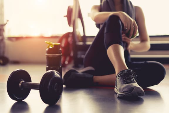 Woman sitting on gym floor next to free weight