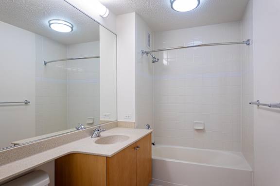 A white bathroom with a sink, mirror, and bathtub.