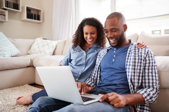 Young Couple Sitting on Floor Together Looking at Laptop
