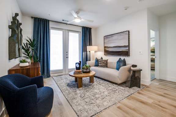 A living room with a blue chair, a white couch, and a rug.