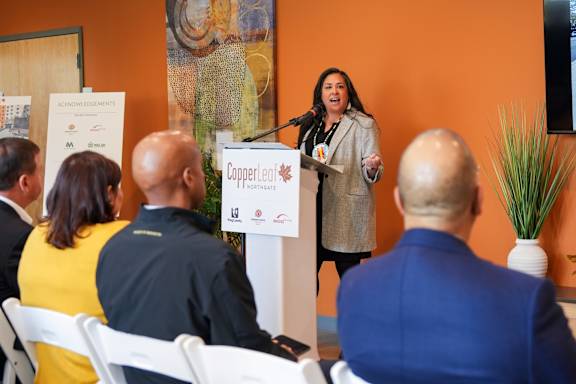 A woman is giving a speech at a podium in front of a group of people.