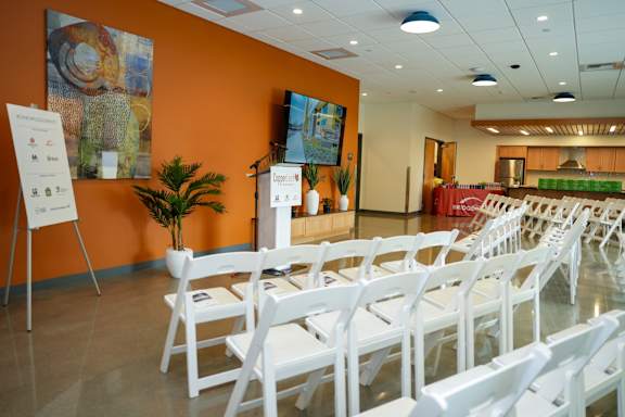 A room with white chairs and a white board on a stand.