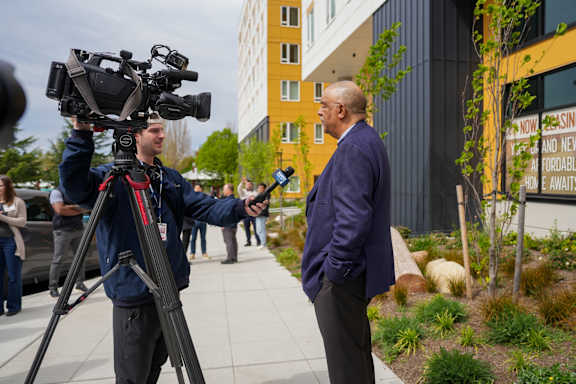 A man in a blue jacket is being interviewed by a camera crew.