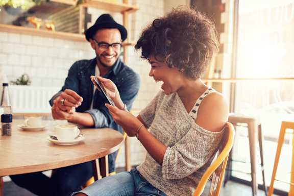Man and Woman Laughing while Having Coffee Together