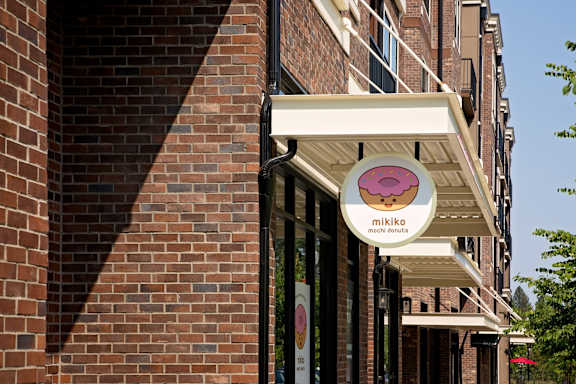 a pink and white sign on the side of a brick building