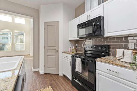 A kitchen with black and white appliances and a marble countertop at Verraso Village Townhomes in Meridian, 83646