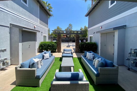 a patio with couches and a table in front of a house