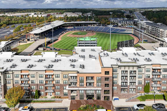 a exterior photo of apartments with baseball field in background