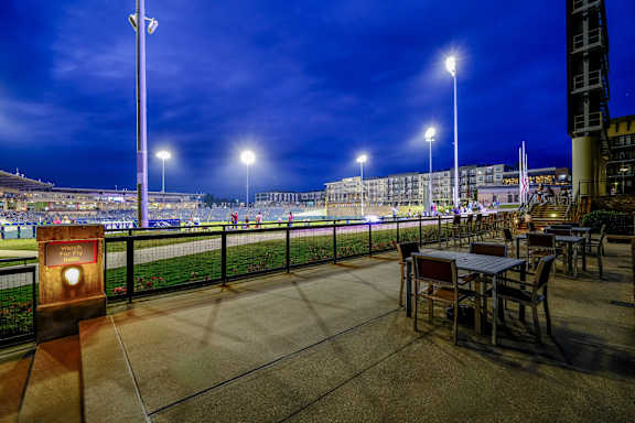 a terrace with tables and chairs overlooking a race track at night