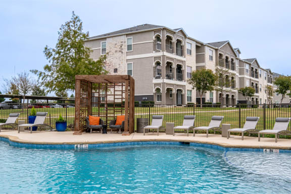 Sparkling blue pool with building exterior at Park 3Eighty in Aubrey, TX