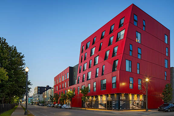 A red building with many windows is lit up at dusk.