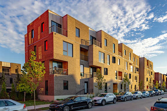 A row of modern apartment buildings with cars parked in front.