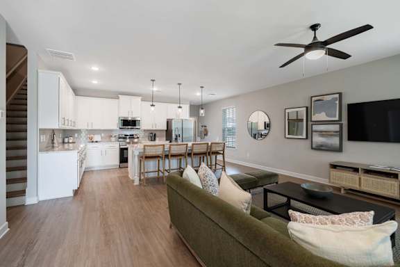 A living room with a green couch and a ceiling fan.