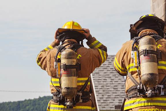 Two firemen in full gear with their backs to the camera.