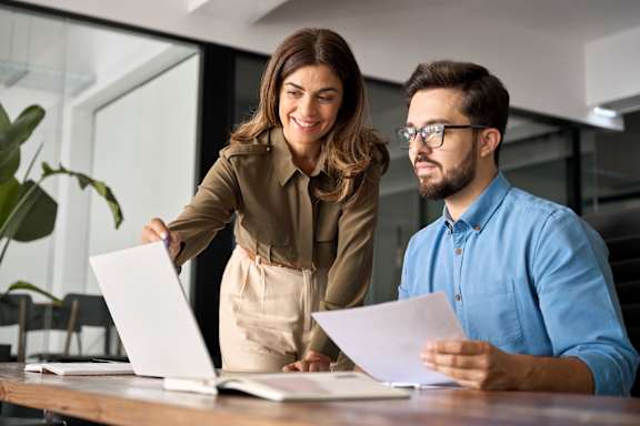 A man and a woman are reviewing documents together at a table.