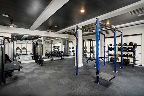 A gym with a variety of equipment including weights and a bench.