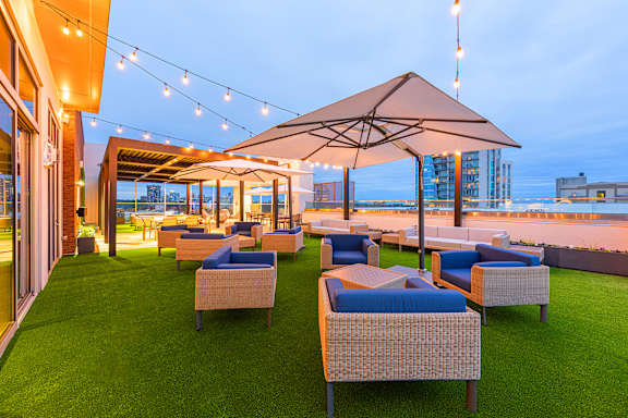A patio with a lawn and chairs under umbrellas.