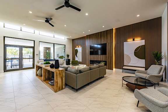 A modern living room with a large sectional sofa, a wooden coffee table, and a ceiling fan.