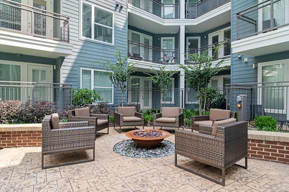A patio with a fire pit and chairs.