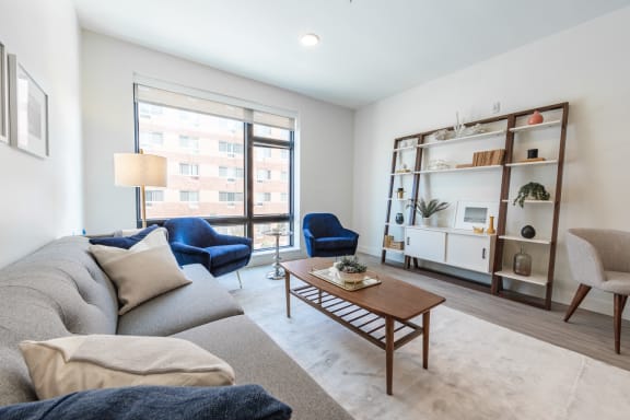 Apartments for Rent in Beverly, MA- Holmes Beverly- Wood-Style Floors with Floor-to-Ceiling Windows and Comfortable Grey Couch