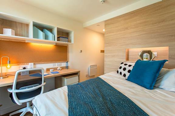 a bedroom with a bed and a desk in a room
