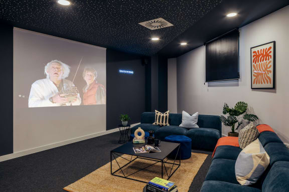 a living room with couches and a screen on the wall