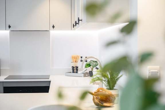 A kitchen with a white countertop and a plant in a glass vase.