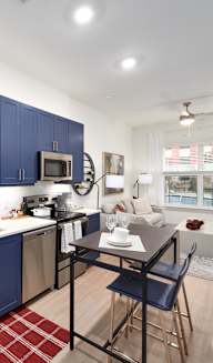 a kitchen and living room with blue cabinets and a red rug at Tapestry West in Richmond, Virginia 23230