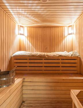 A wooden sauna with a bench and bucket.