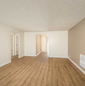 Empty room with wooden flooring and white walls.