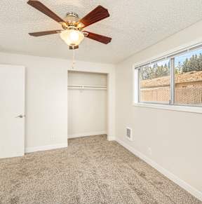 A room with a ceiling fan and a window showing an outdoor view.
