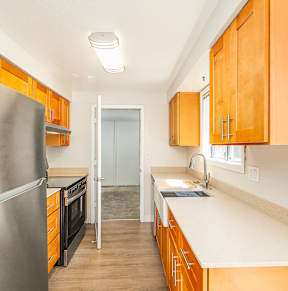 A kitchen with wooden cabinets and a stainless steel refrigerator.