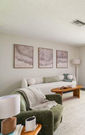 A living room with a white couch, a wooden coffee table, and a dining table with chairs.