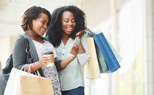 three women walking down the street with shopping bags