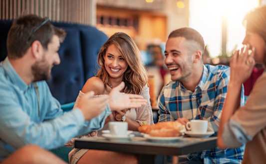 a group of people sitting around a table talking and laughing