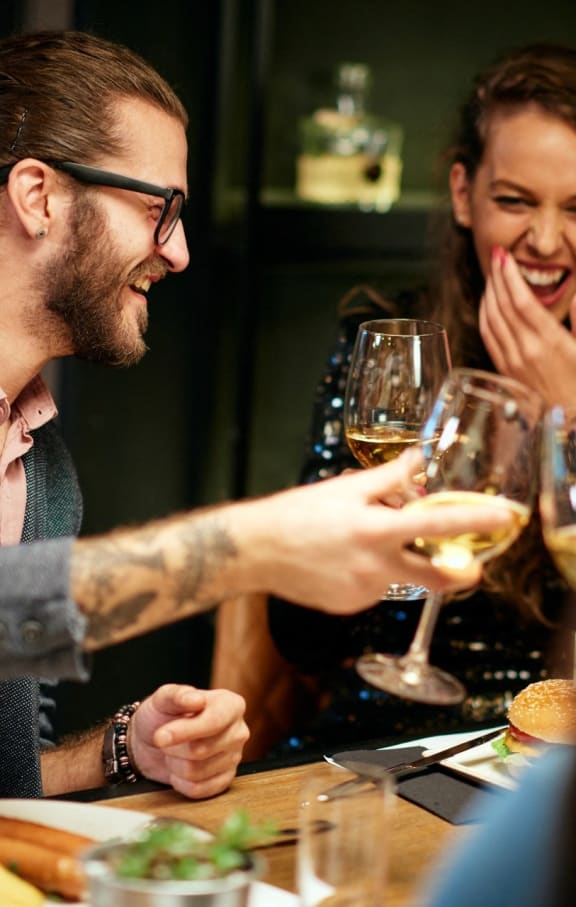 Man and Woman Smiling while Drinking Wine and Having Dinner Together