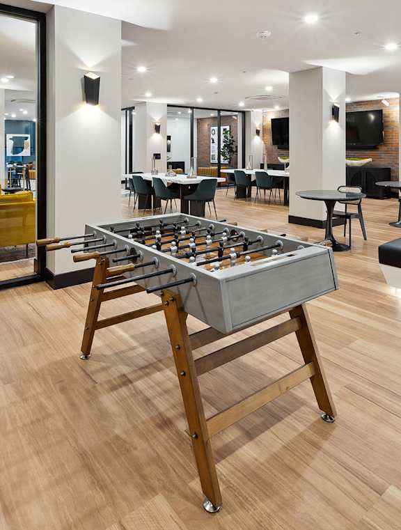 A modern living room with a wooden floor and a dining area in the background.