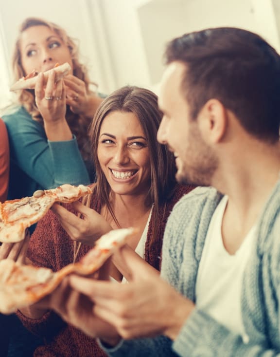 Friends Smiling while Eating Pizza and Having Drinks Together
