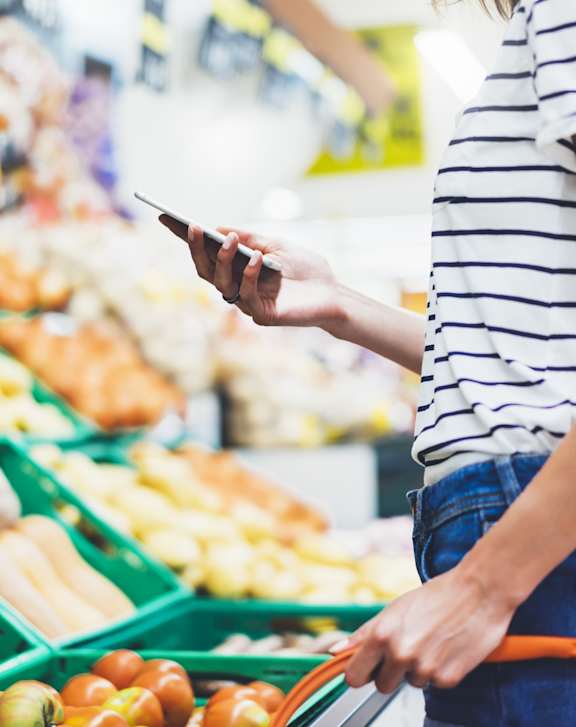 Woman Holding Phone while Shopping in Grocery Store