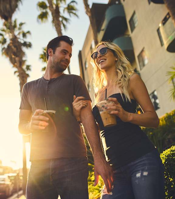 a man and a woman walking down the street with drinks in their hands at Waverly, Los Angeles, CA