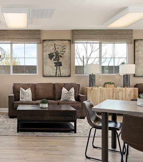 A living room with brown furniture and a ceiling fan.