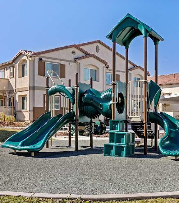 A playground with a green slide and a green canopy.