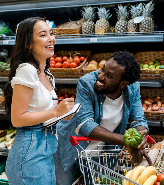 Man and Woman Smiling while Grocery Shopping Together