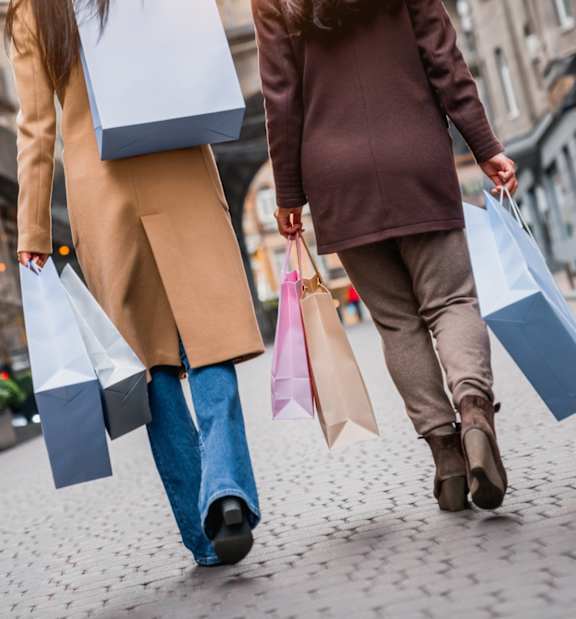 Two people walking down a street carrying shopping bags.