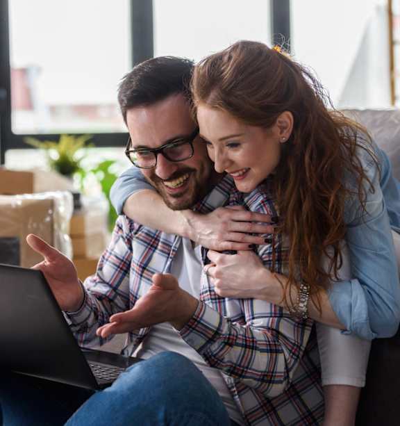 Man and Woman Hugging Each Other Smiling and Looking at Laptop