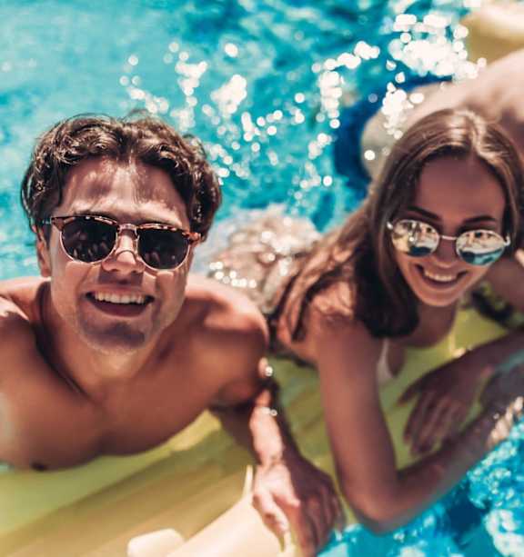 Three people are floating on yellow rafts in a blue pool.