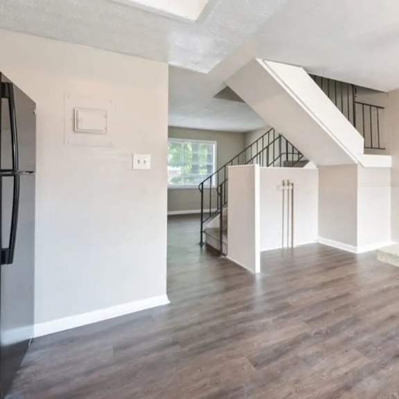 A kitchen with a refrigerator, a counter, and a staircase.