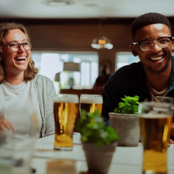 Friends Sitting at Table Together Smiling and Having Drinks