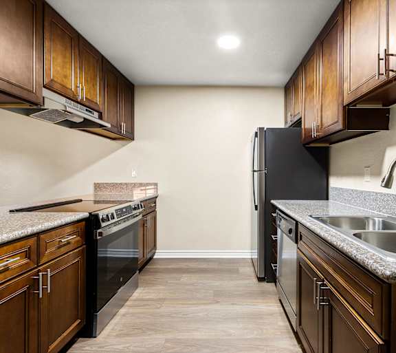 A kitchen with brown cabinets and a black refrigerator.